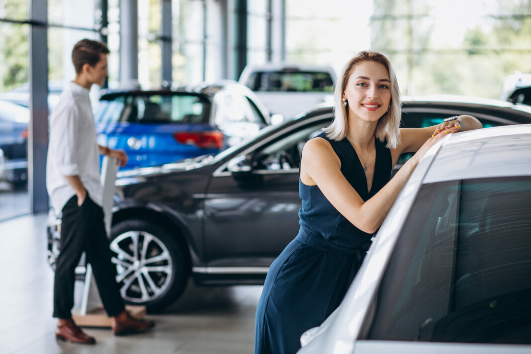 Young couple choosing a car in a car show room